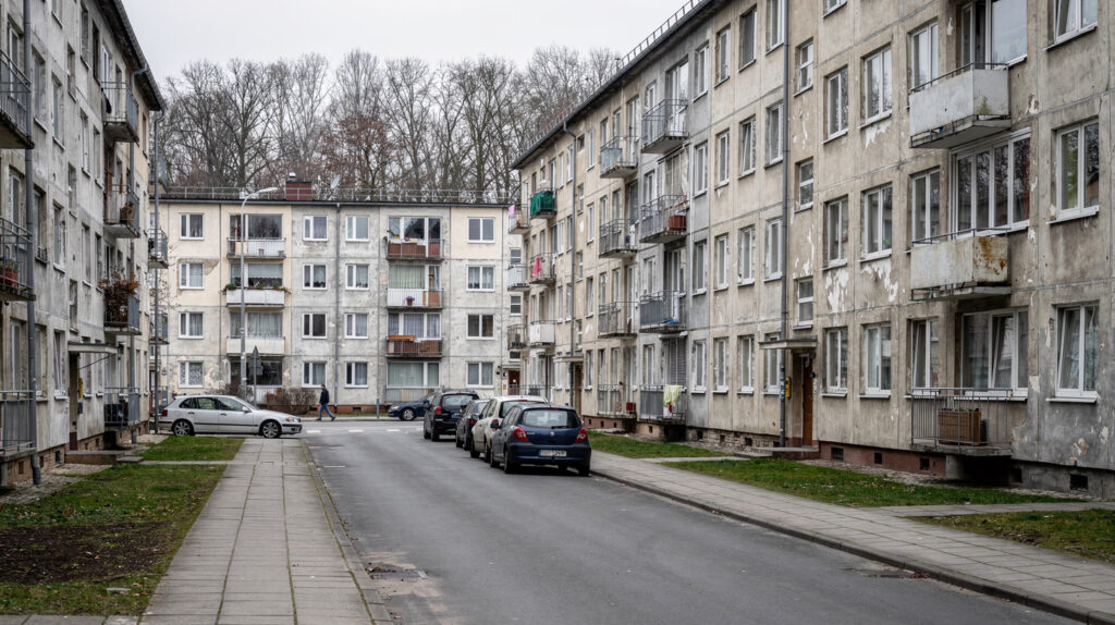 Ulica z blokami z wielkiej płyty w małym polskim mieście, samotny przechodzeń na chodniku, pochmurny jesienny dzień